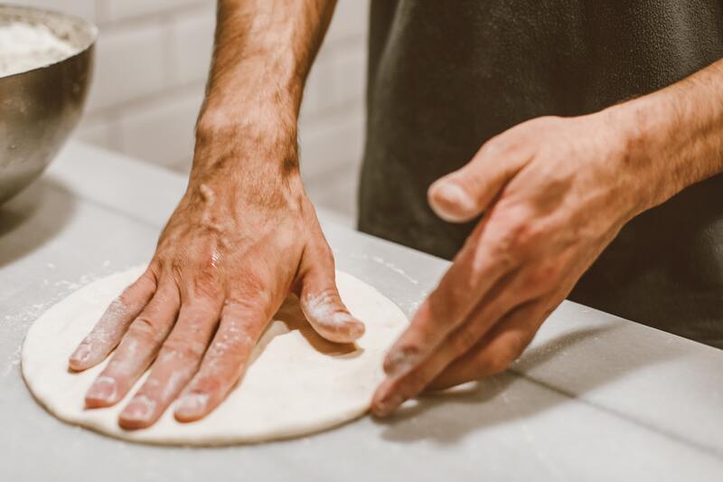 mani di un pizzaiolo che lavora
